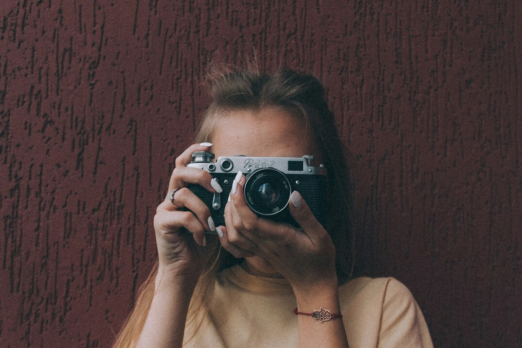 Woman looking through a professional video camera viewfinder in a studio