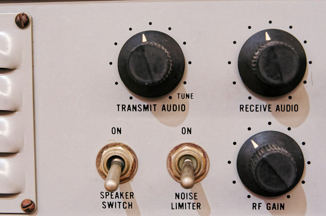 Close-up of a broadcast audio mixing desk with faders and buttons